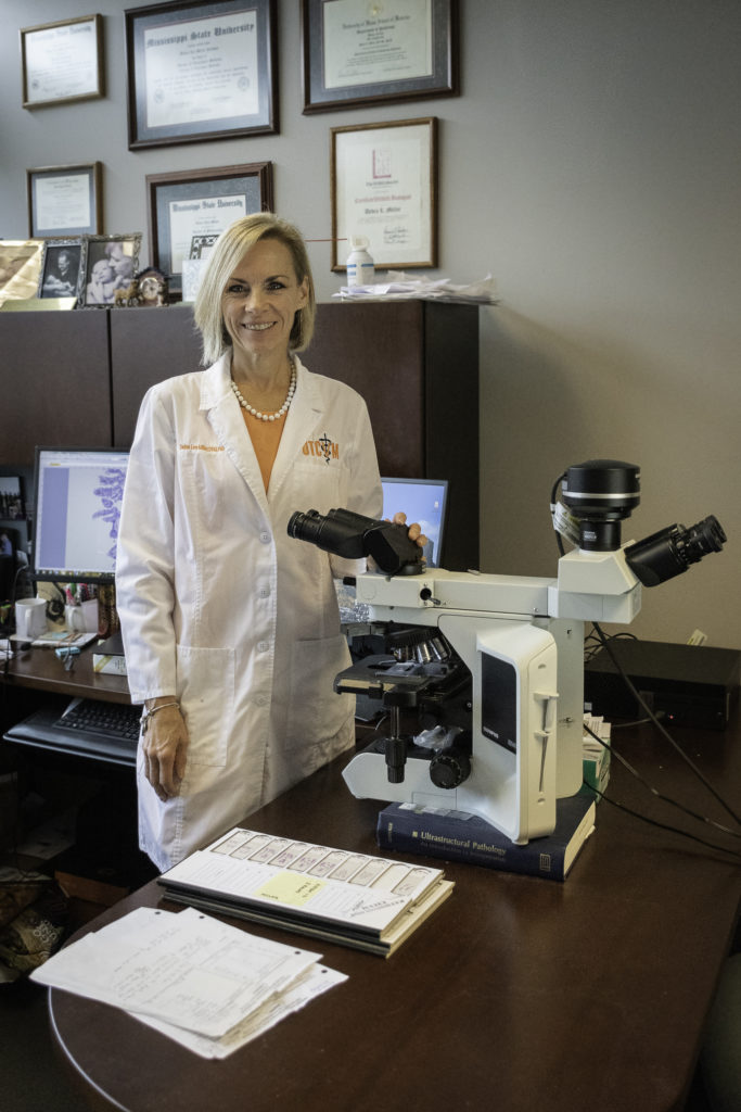 Deb Miller stands in her office lab by a microscope.