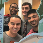 A group of students holds up a selfie board for a photo.